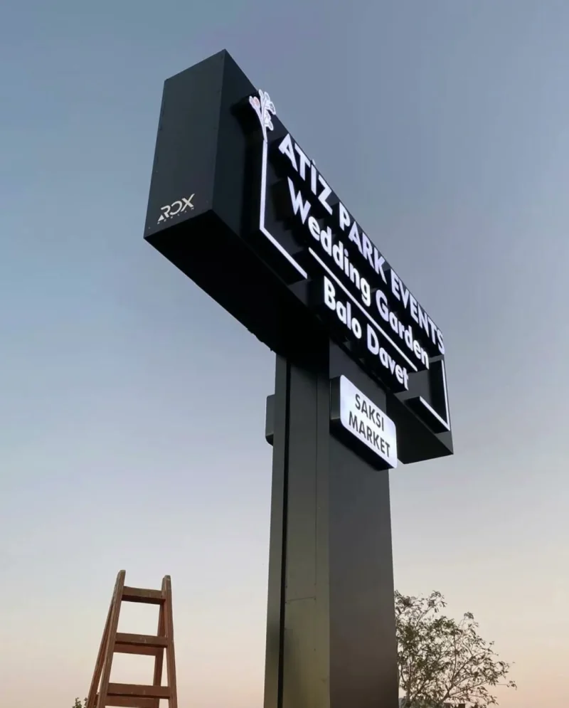 Akşam saatlerinde parlayan siyah kasetli ışıklı totem tabela