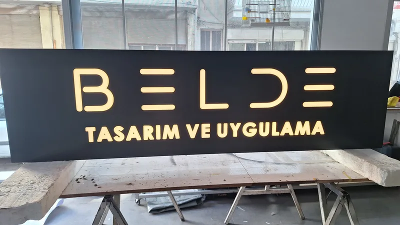 Mat siyah kompozit zeminde gün ışığı aydınlatmalı oyma tabela